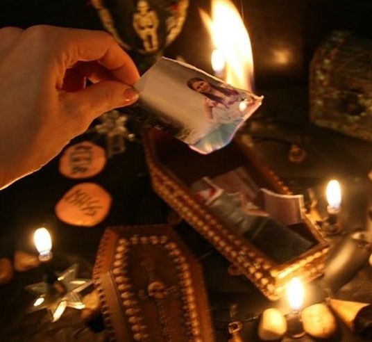 Ritual de amarre de amor con foto siendo quemada sobre un altar con velas y elementos esotéricos.